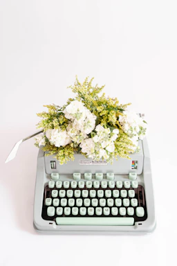 A softly lit image of a vintage typewriter with a romantic letter beside a delicate bouquet of flowers.