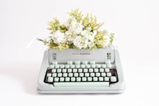 a typewriter with a bunch of flowers on top of it
