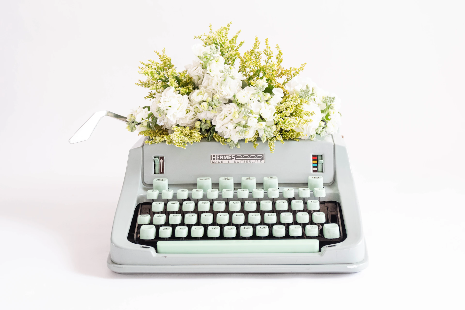 a typewriter with a bunch of flowers on top of it