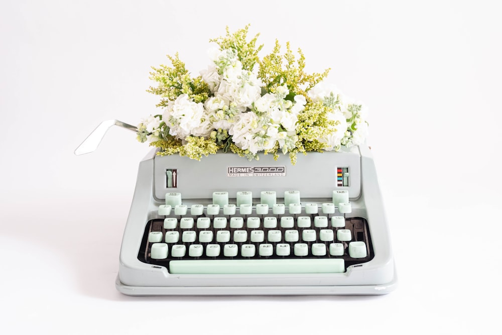 uma máquina de escrever com um ramo de flores em cima dela