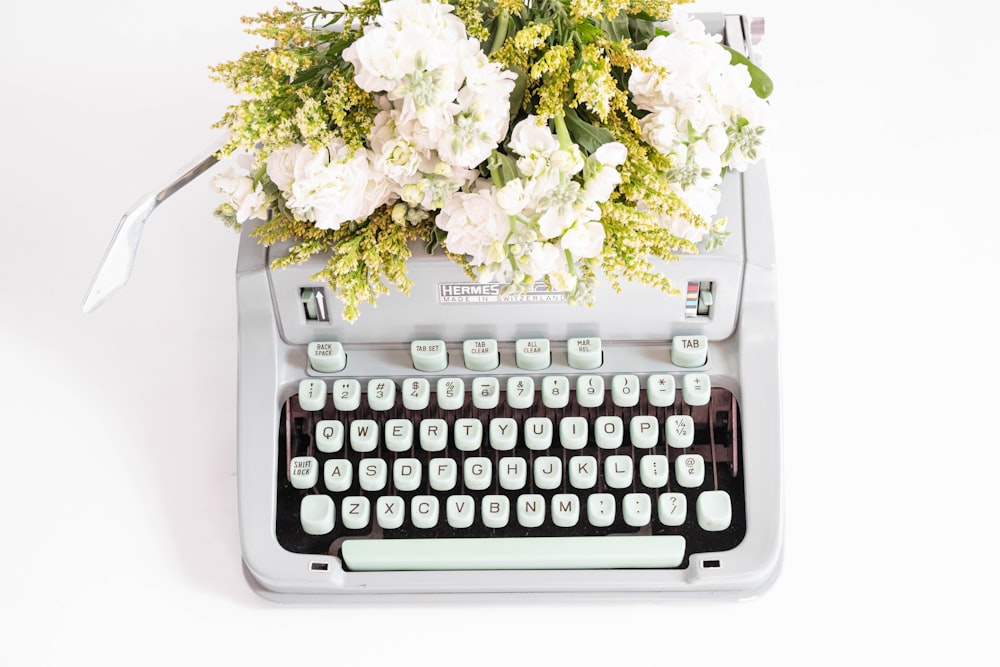 a typewriter with a bunch of flowers on top of it