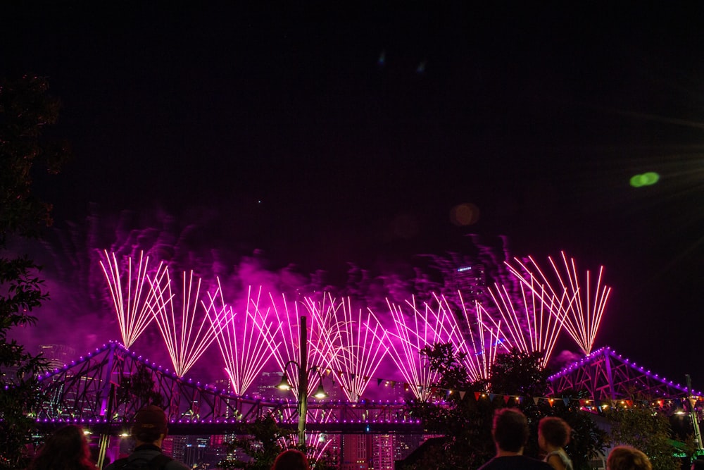 a group of people watching fireworks on a bridge