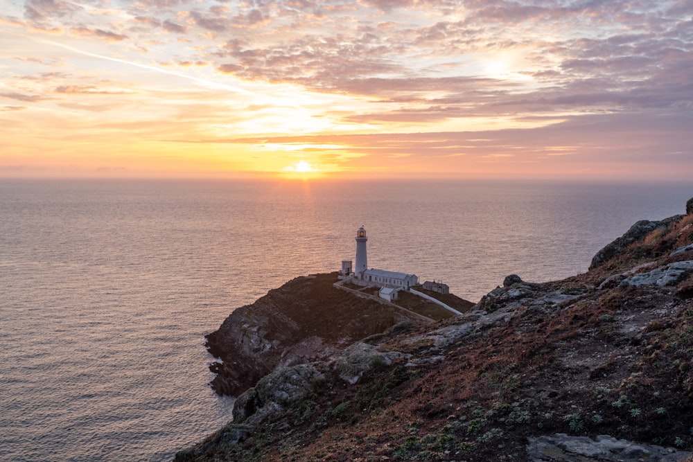 a lighthouse sitting on top of a cliff next to the ocean