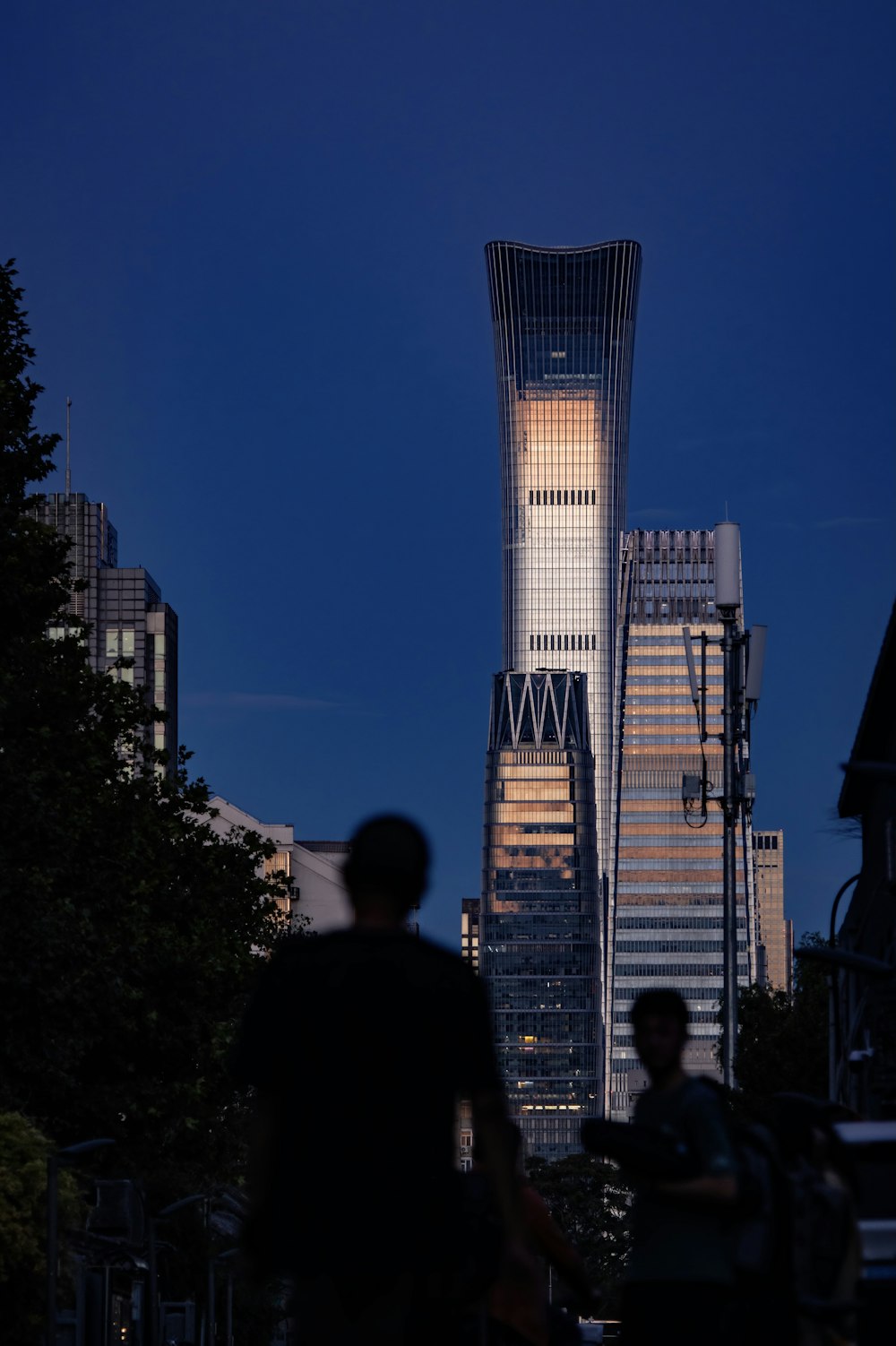 a couple of people walking in front of a tall building