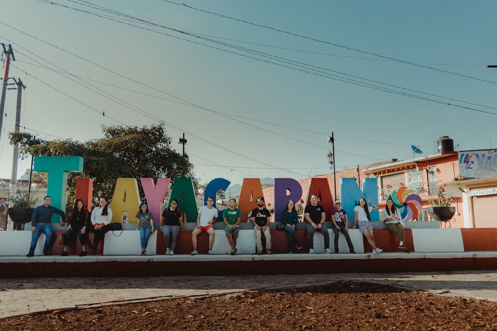 a group of people sitting in front of a large sign