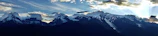 A panoramic view of a mountain range under a dramatic sky, seen on a hiking trip.