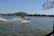 Man riding a jet ski with splashes of water under a bright blue sky.