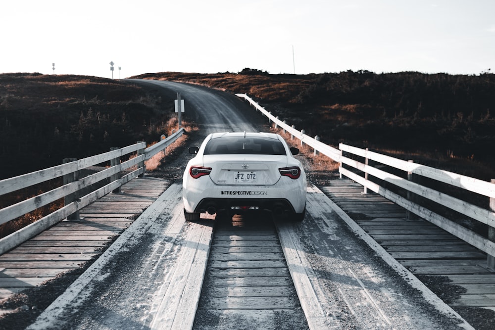 a white car driving down a road next to a bridge