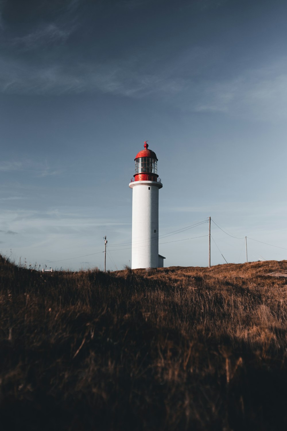 a white and red lighthouse sitting on top of a hill