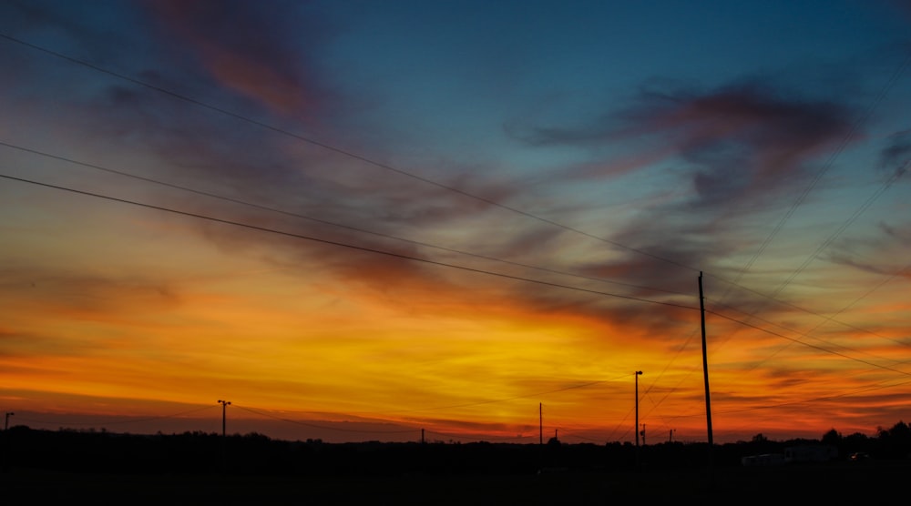 the sun is setting behind power lines and telephone poles