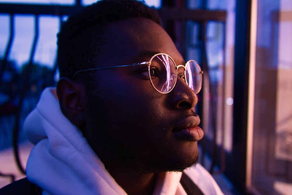 a man wearing glasses looking out a window