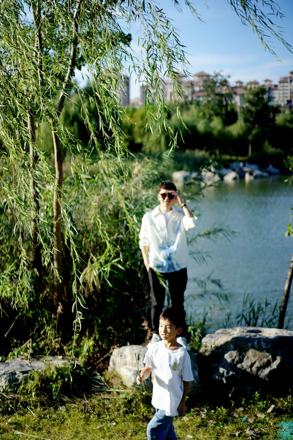 a man standing next to a little boy near a river