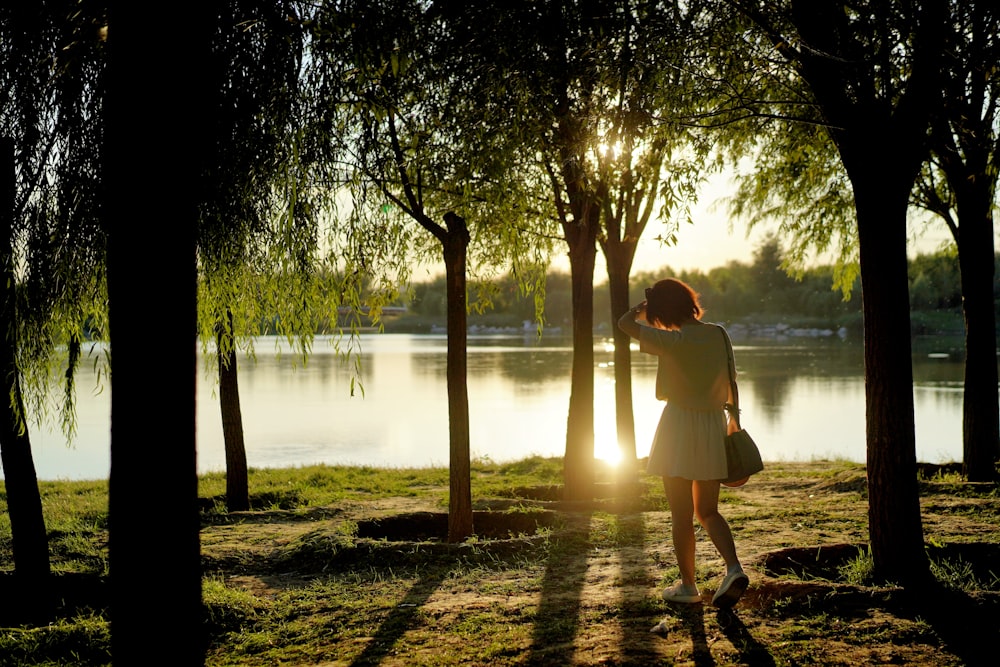 a woman in a white dress standing in a park