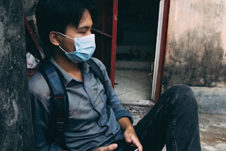 a man sitting on the ground wearing a face mask