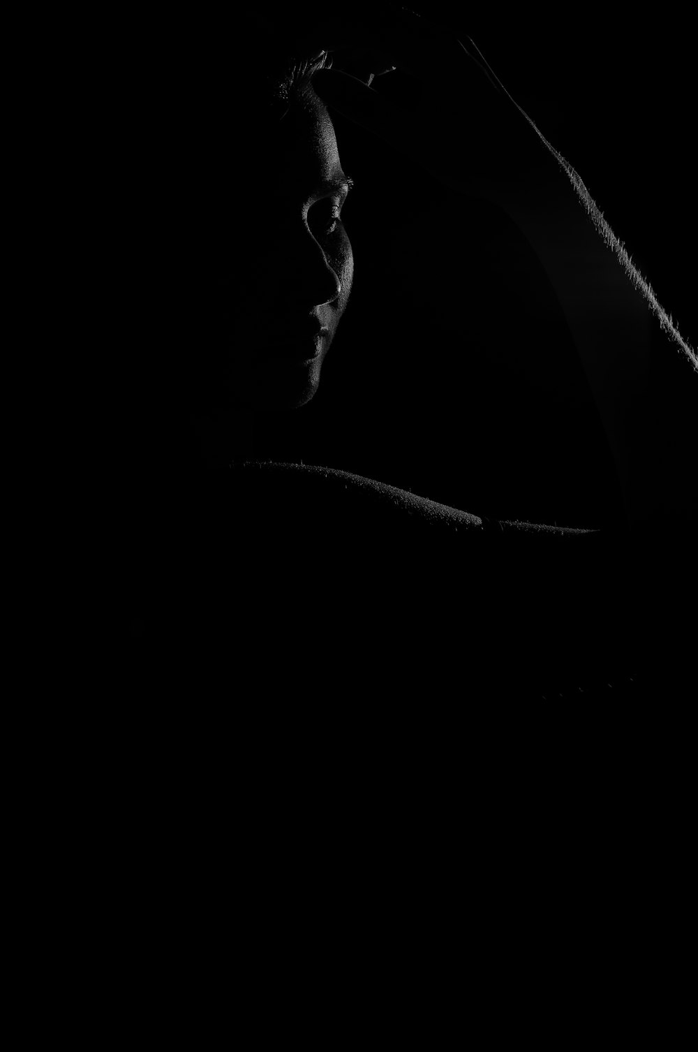a man in the dark holding a cell phone to his ear
