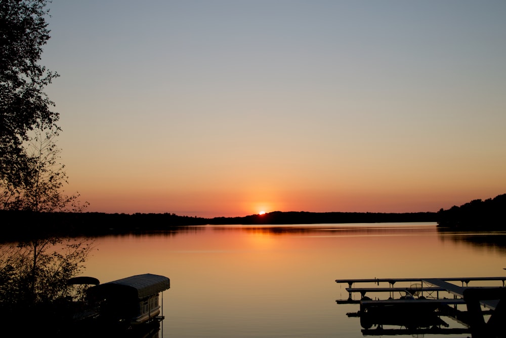 the sun is setting over the water and boats are docked