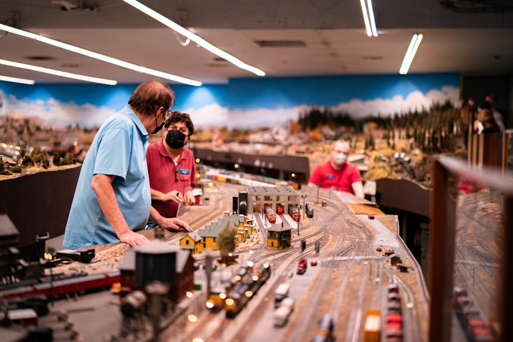 a couple of men standing next to a model train set