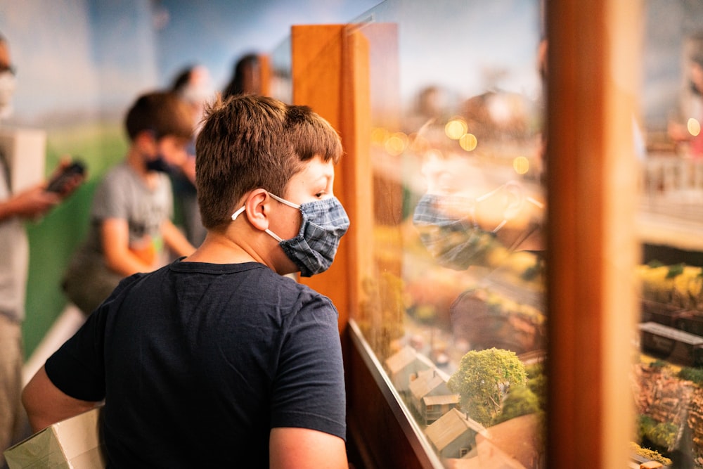 a young boy wearing a face mask looking at a display case