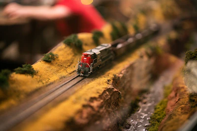 A close-up of a detailed model train engine on a miniature track with scenic background.
