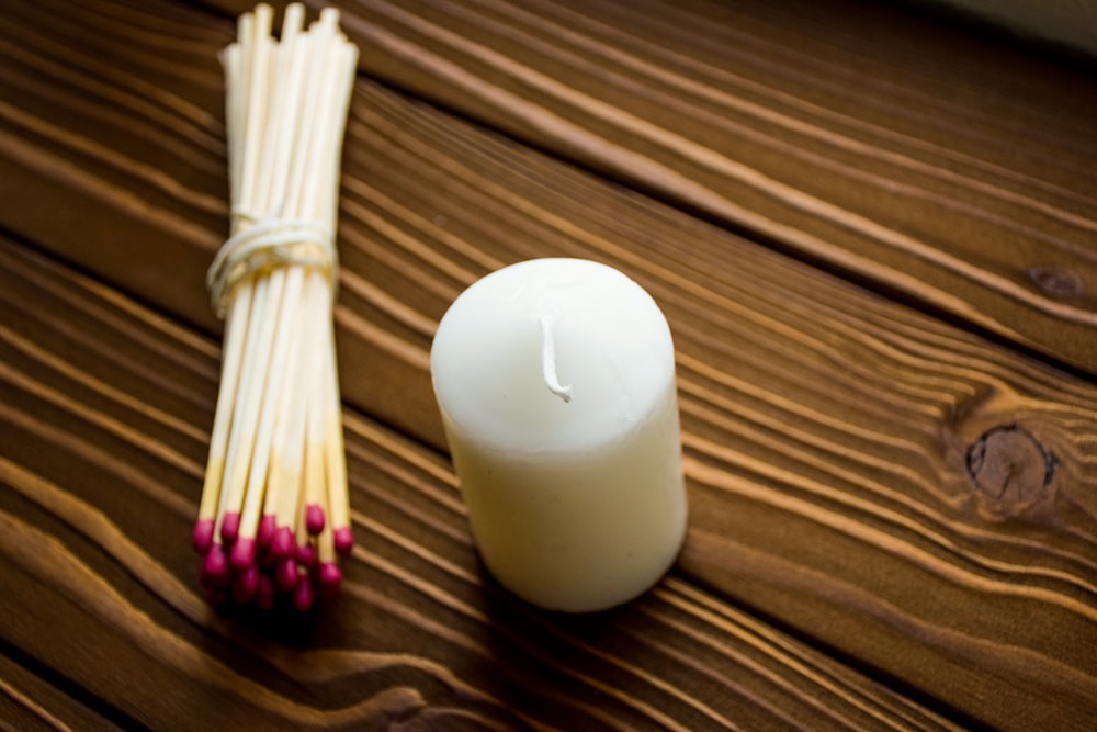 a white candle sitting next to a bundle of matches