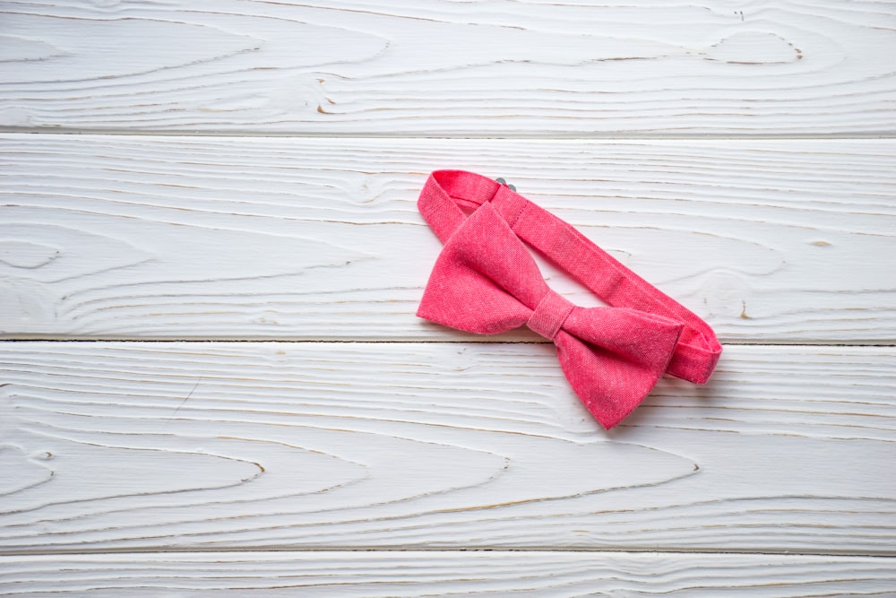 a pink bow tie laying on top of a white wooden floor