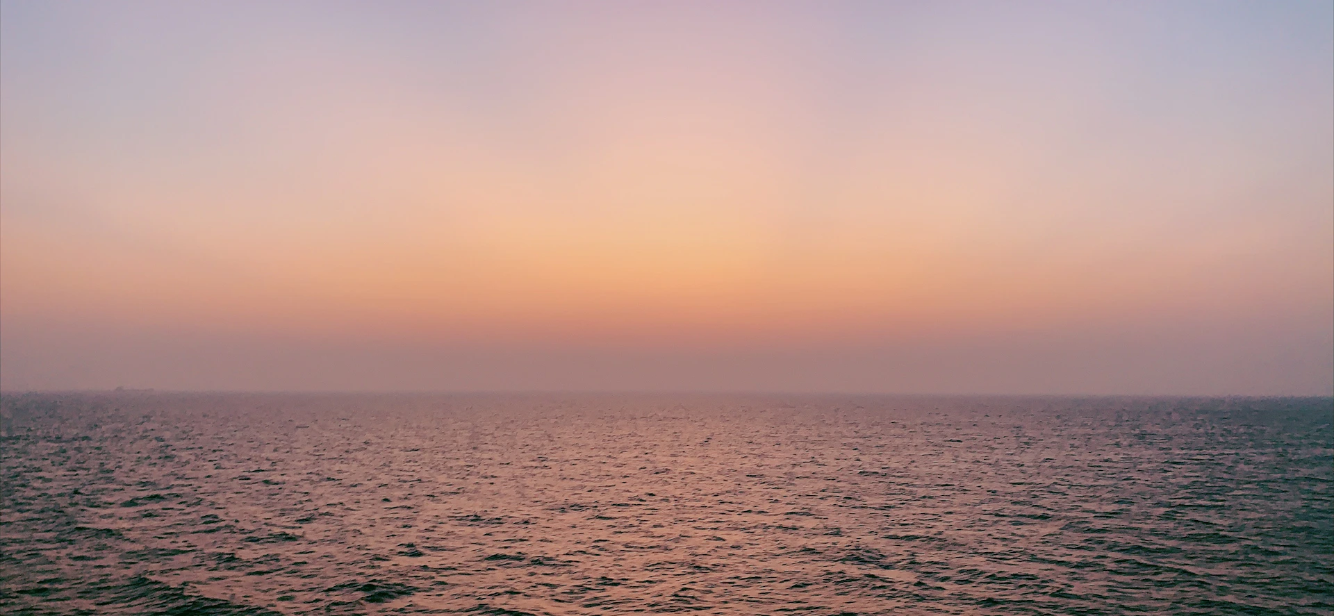 A serene carousel slide showing a soft gradient sunrise over a calm ocean horizon with gentle waves.