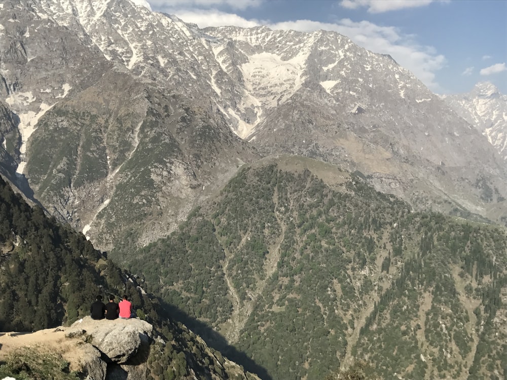 a couple of people sitting on top of a mountain