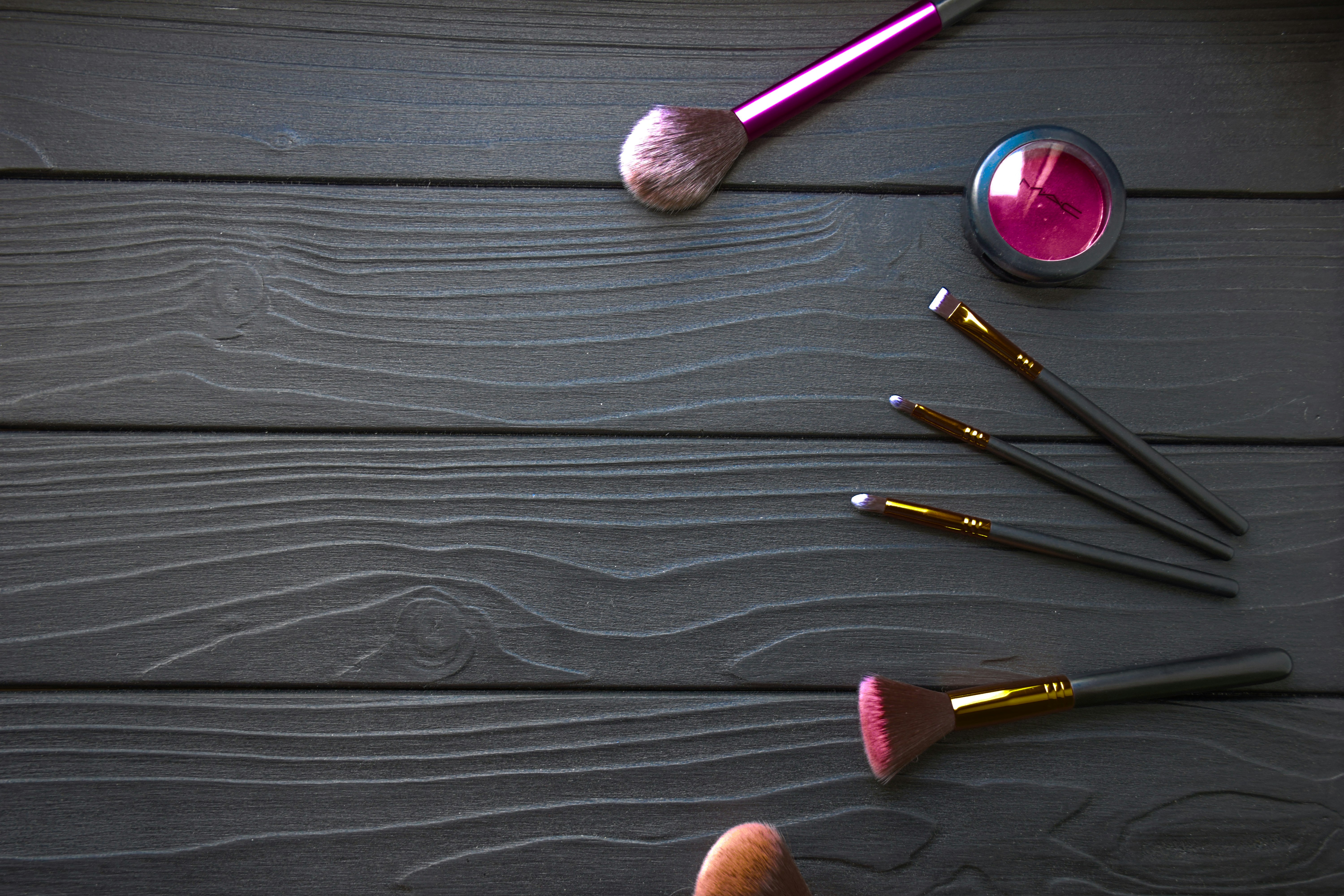 a person's hand is holding a brush and a set of makeup brushes