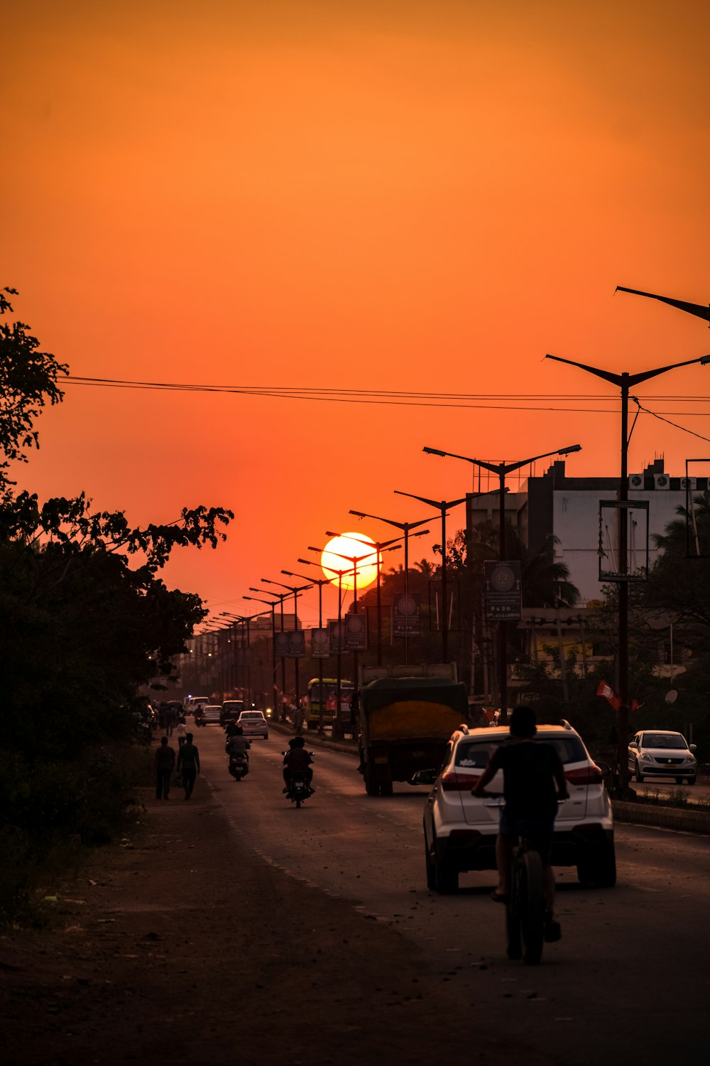 a person riding a bike down a street at sunset