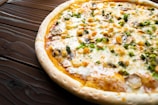 Close-up of a freshly baked pizza with vibrant toppings on a wooden table.