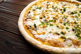 A close-up of a freshly baked pizza with bubbling cheese and vibrant toppings on a rustic wooden table.