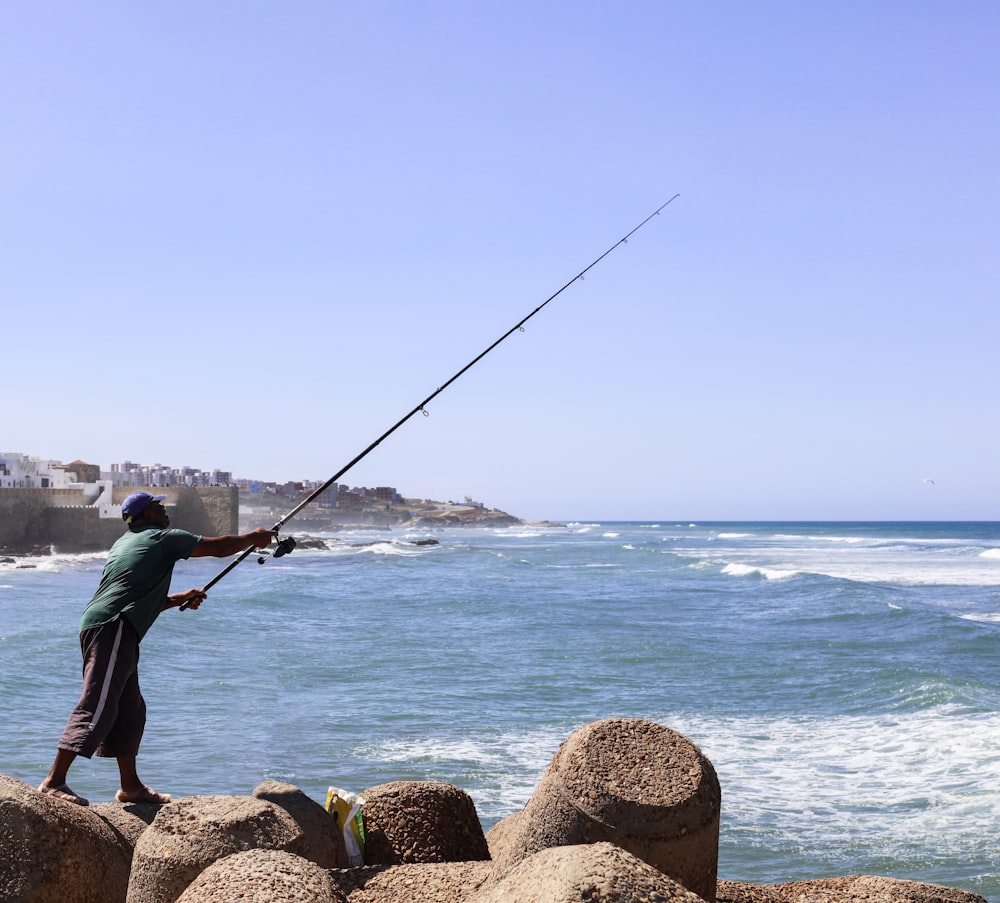 a man standing on a rock while holding a fishing rod