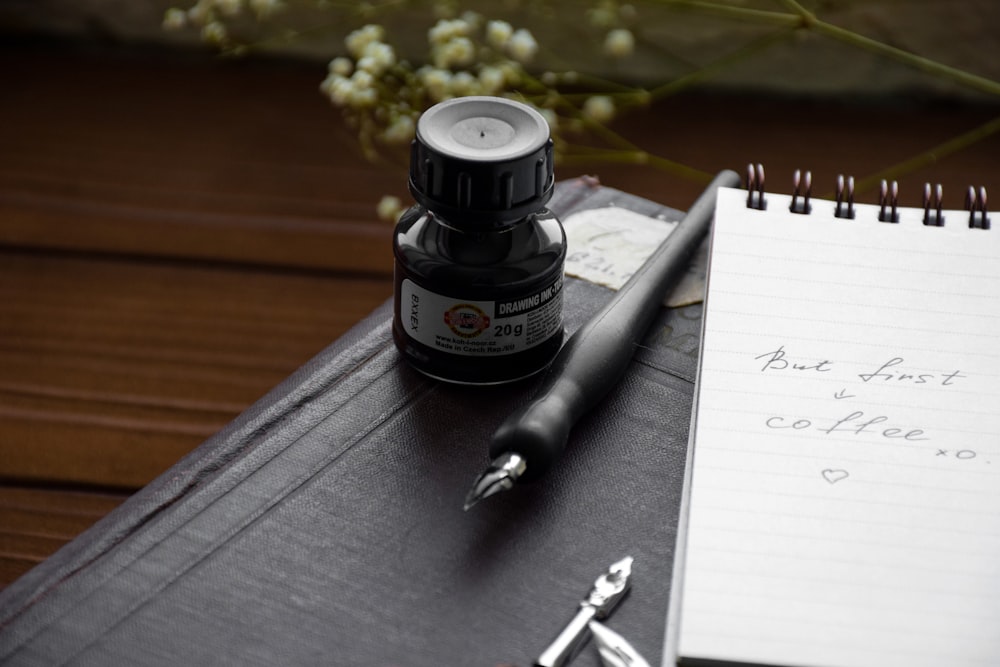 a notepad, pen, and ink bottle sitting on a desk