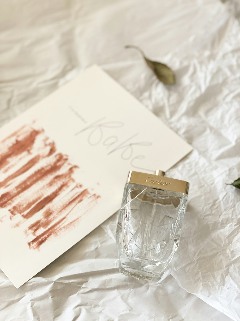 a bottle of perfume sitting on top of a white sheet