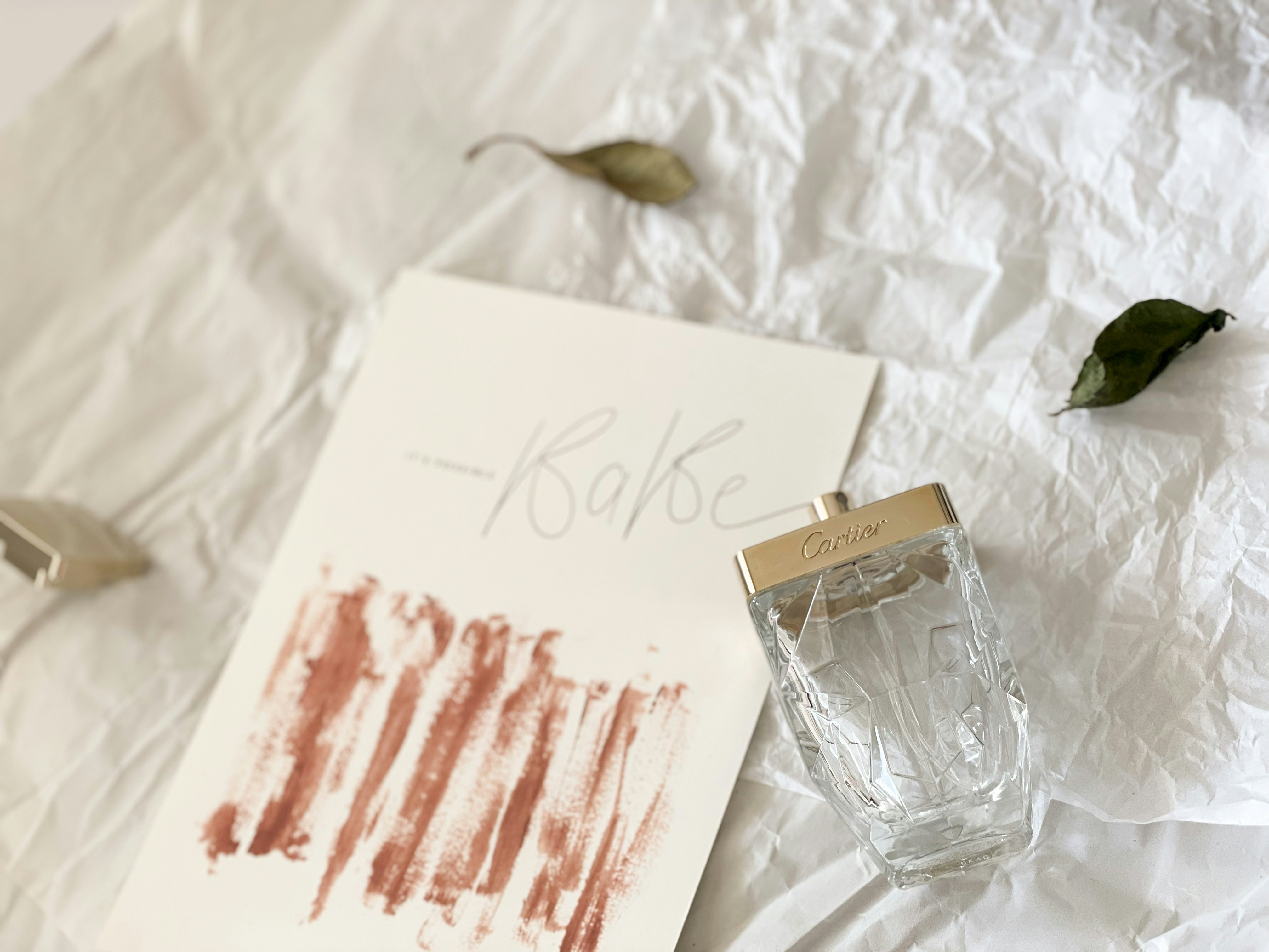 a bottle of cologne sitting on top of a white sheet