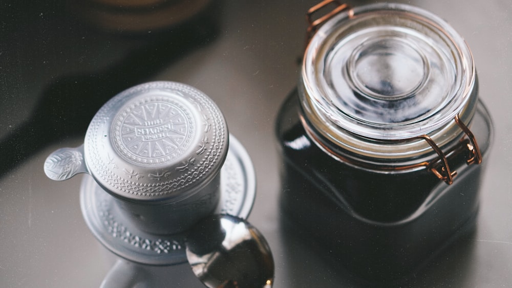 a jar of liquid sitting next to a spoon