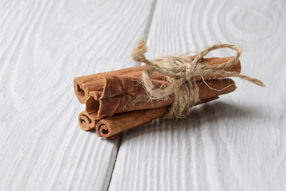 cinnamon sticks tied with twine on a white wooden surface