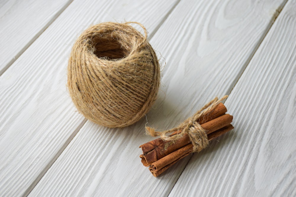 a roll of twine and cinnamon sticks on a white wood floor