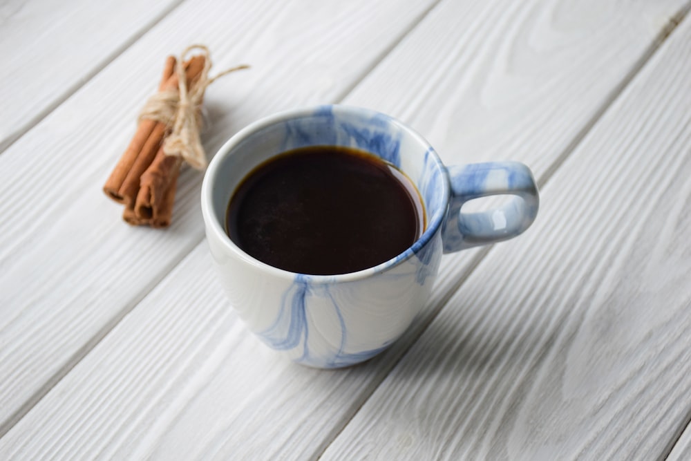 a cup of coffee next to cinnamon sticks