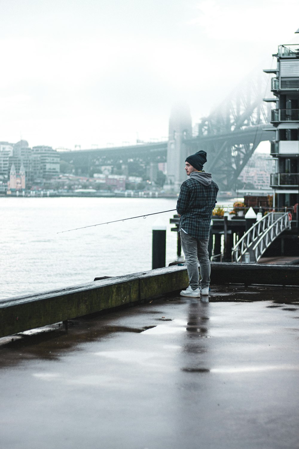 a man standing on a dock with a fishing rod