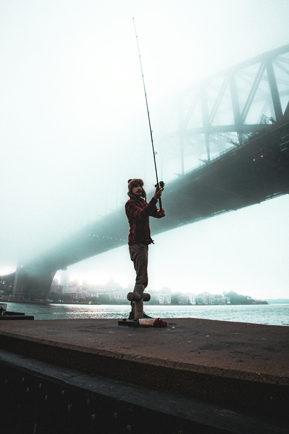 a man standing on a dock holding a fishing pole