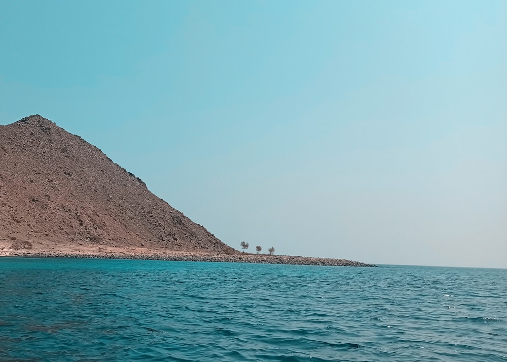a large hill of sand sitting on top of a body of water