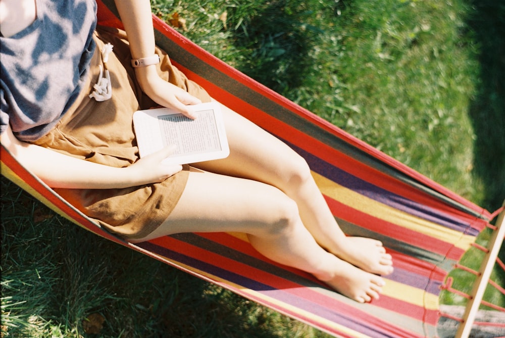 a woman sitting in a hammock reading a book