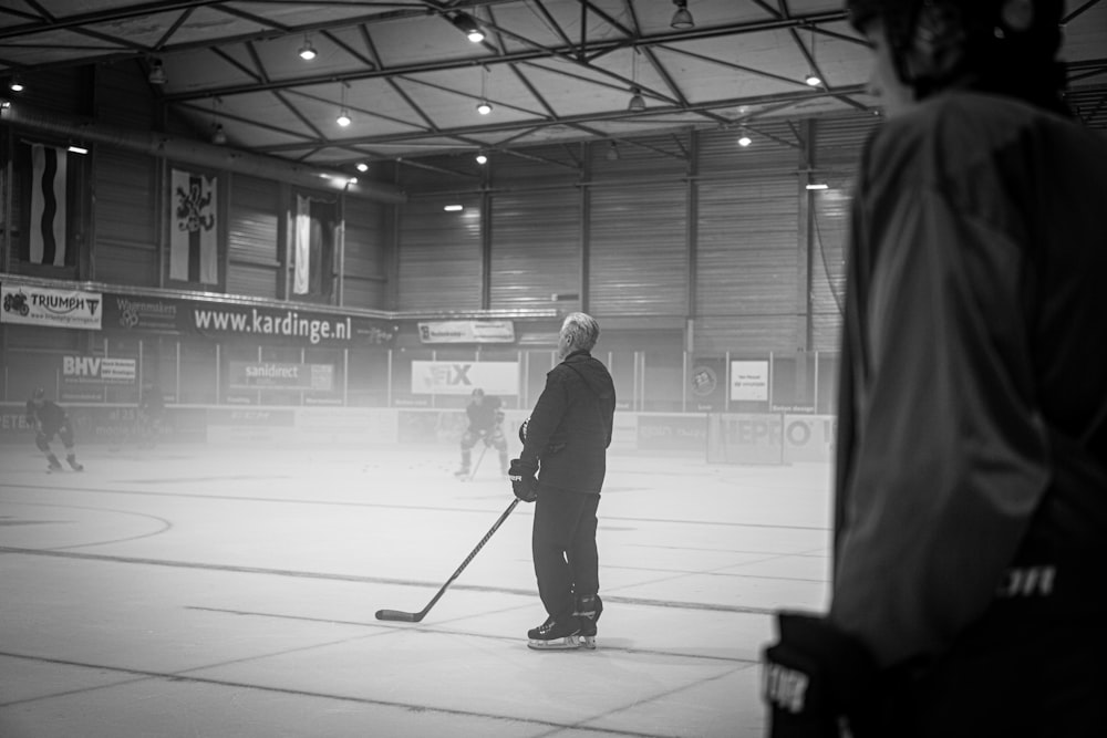 Un uomo in piedi su una pista di hockey con in mano un bastone da hockey