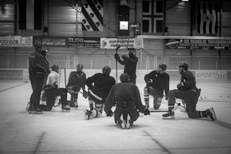 a group of men standing around each other on top of an ice rink