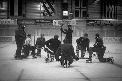 a group of men standing around each other on top of an ice rink