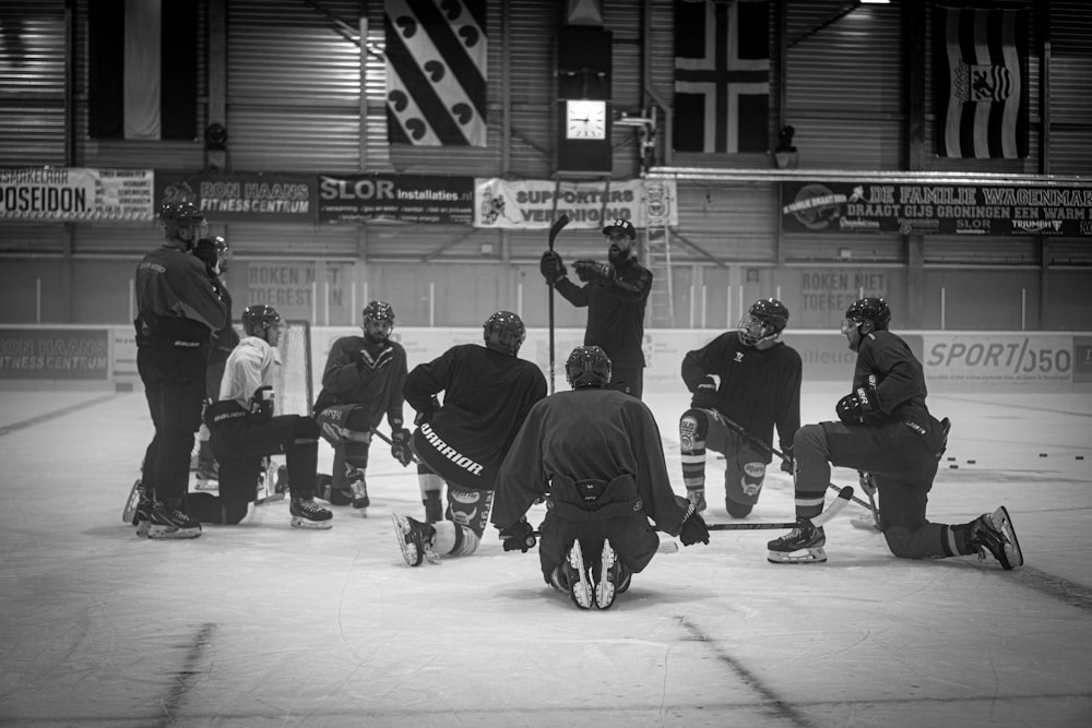 a group of men standing around each other on top of an ice rink