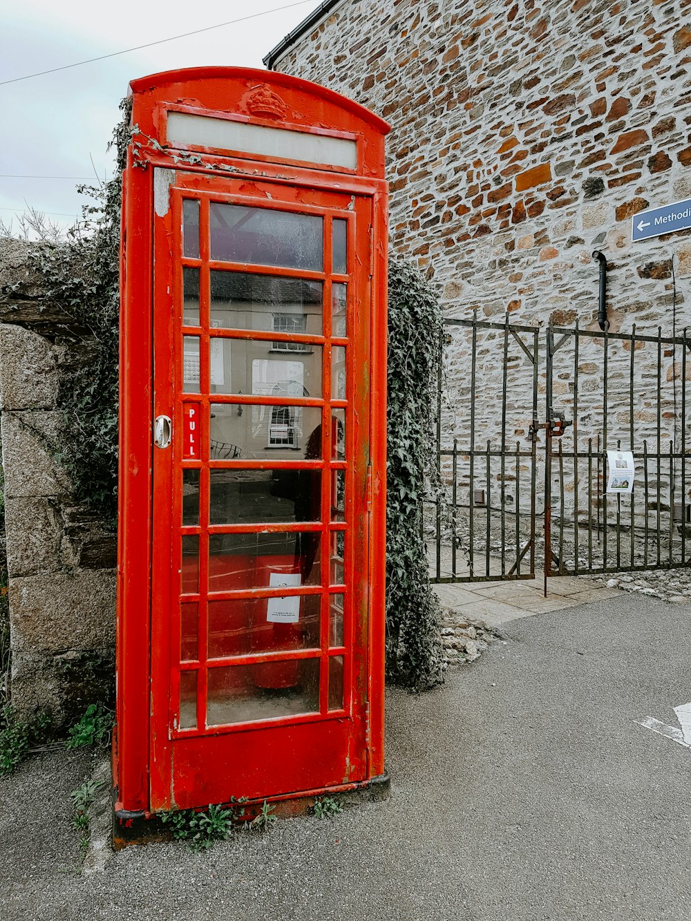 a red phone booth sitting next to a stone building