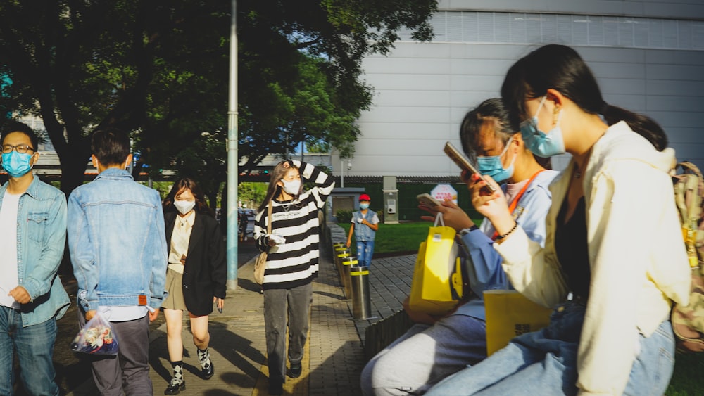 a group of people wearing face masks on a sidewalk