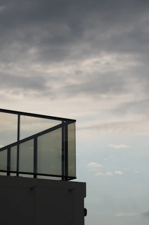 Modern glass and aluminum railing installation on a residential balcony at sunset.